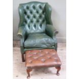 A green leather upholstered wing back armchair in George III style together with a brown leather