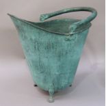 A verdigris finish coal bucket with swing handle and on three paw feet
