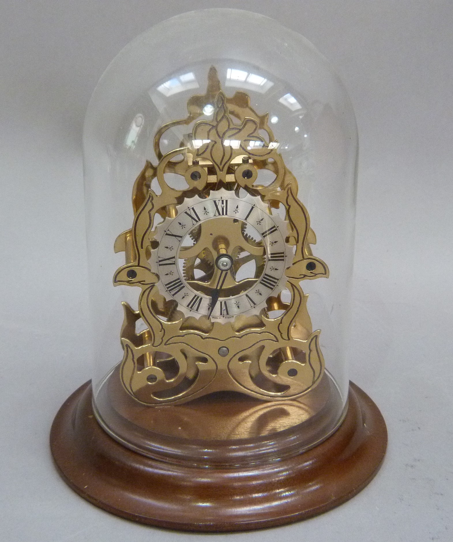 A reproduction skeleton clock with engraved brass plates, single train movement, the shaped silver