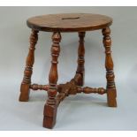 A fruit wood oval topped stool with shaped carrying handle on well turned and block legs joined by
