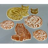 Six ceramic plaques in the shape of cats glazed in cinnamon and amber, various sizes
