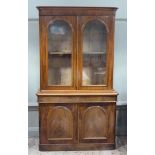 A Victorian mahogany bookcase with shallow cornice and figured frieze, the arched glazed doors above