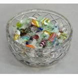 A cut glass bowl containing a large quantity of coloured glass sweets (quantity)