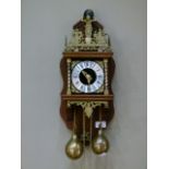 A reproduction 17th century style wall clock with wooden back plate atlas finial three quarter brass