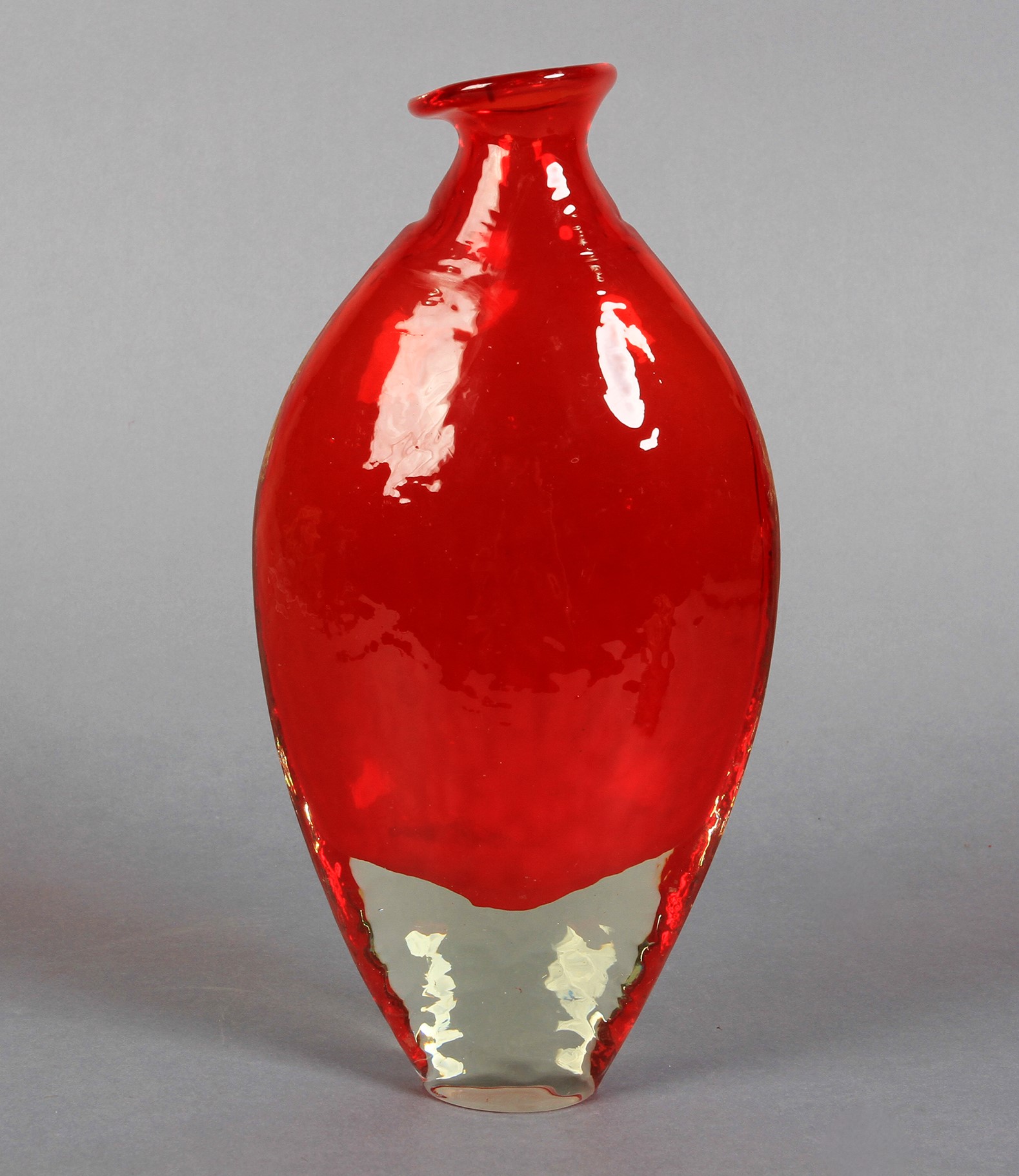 An art glass flask form vase of textured red glass with clear base, pinched angled rim, 21.5cm high