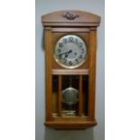 An oak wall clock with arched top, the door with circular glazed aperture revealing silvered dial