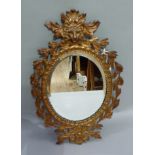 A patinated cast iron wall mirror, the top with lion mask holding a garland of leaves, the base with