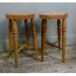 A pair of oak topped stools, the circular tops with reeded edges above turned beech legs joined by