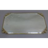 An Edwardian canted rectangular brass framed wall mirror with bevelled plate engraved stylised