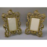 A pair of gilt painted metal photograph frames with broad pierced foliate scroll borders, the