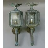 A pair of reproduction lacquered brass coaching lanterns with bird finials, the cantered square
