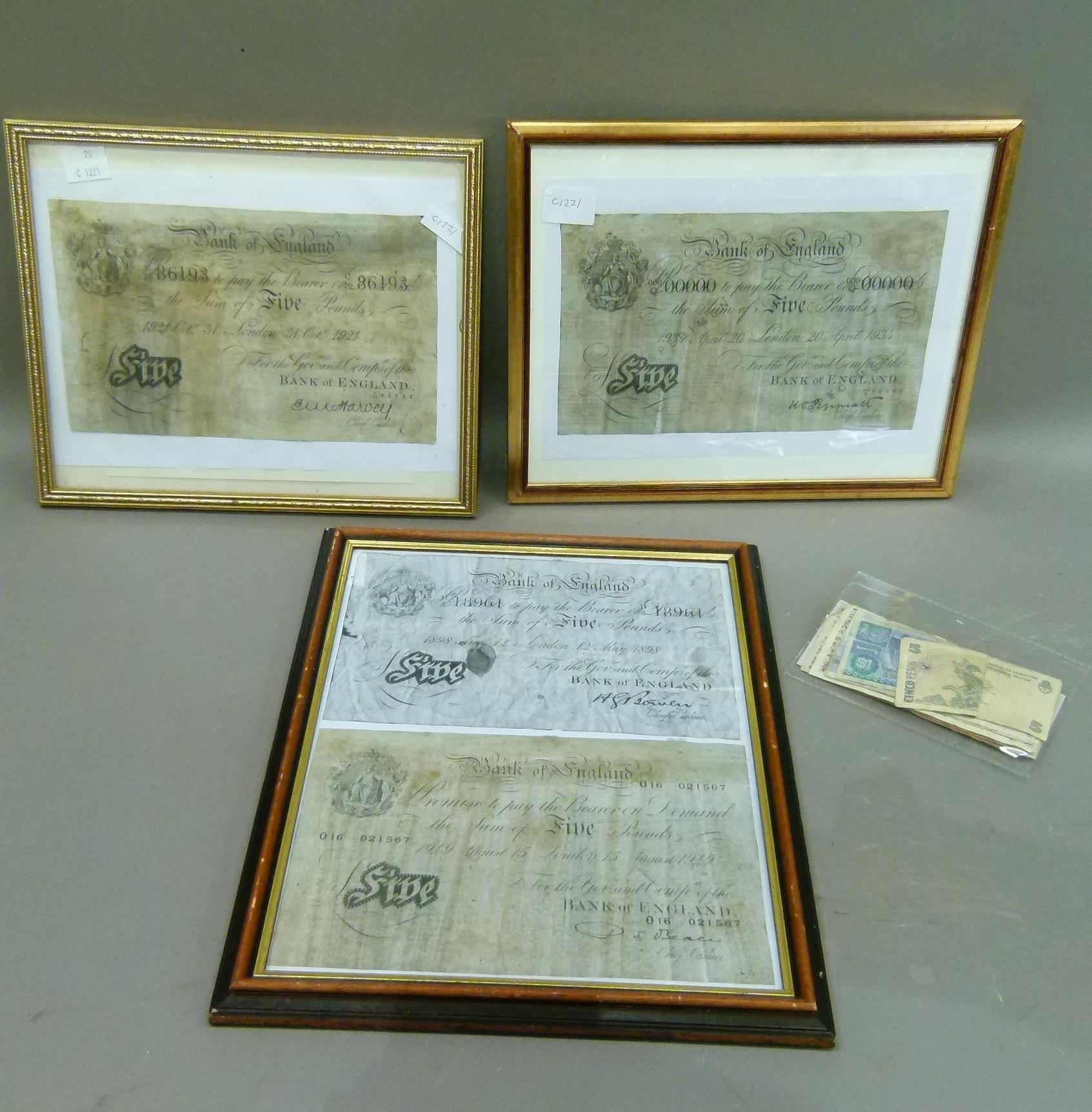 Three framed photocopies of five pound notes and packet of foreign notes