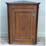 A 19th century oak hanging corner cupboard having a dentil cornice above a single field panel door