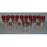 A suite of cranberry and gilt decorated glassware including champagne coupes, sherries and liqueurs,