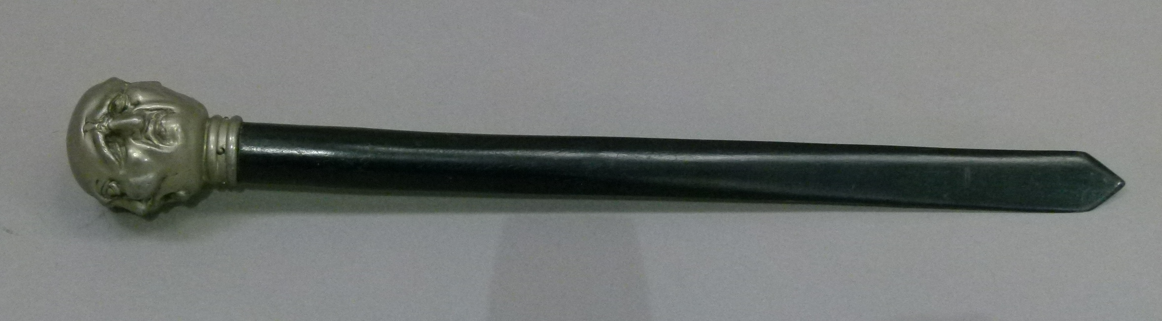 A letter opener with white metal pommel cast as four grotesque faces, 36cm long