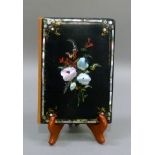 A Victorian black papier mâchê letter folio, the front inlaid in mother of pearl and painted with