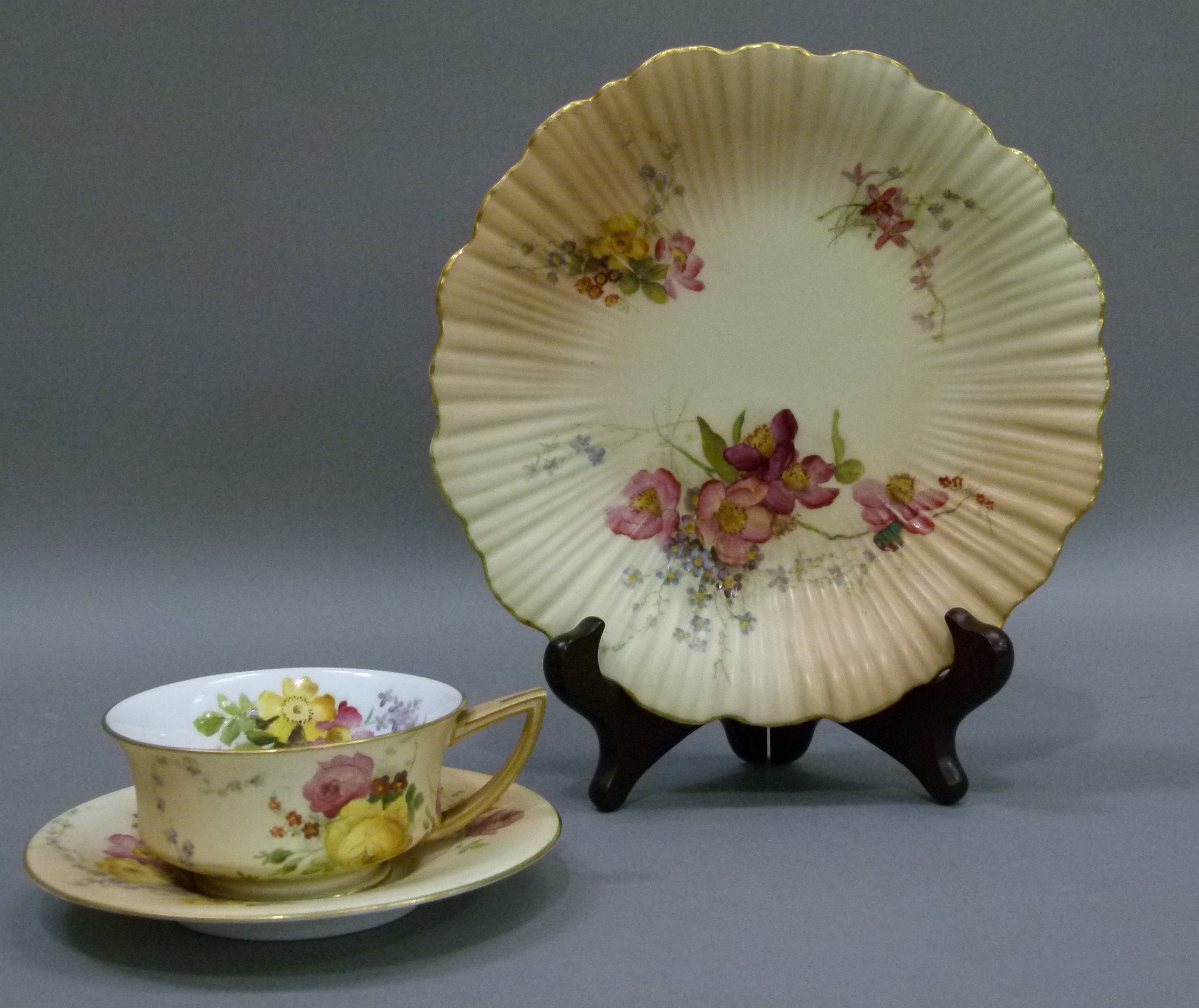 A Royal Worcester shaped circular cabinet plate, painted with floral sprays on a shaded apricot