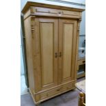 A Continental pine wardrobe, the flared cornice above a frieze centred on a turned roundel flanked