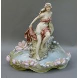A Royal Dux figure of a diaphonously clad young woman seated on a rocky outcrop with pink floral