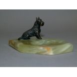 A bronzed white metal Scottie dog ash tray, the small figure on a coffin shaped onyx base with