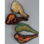Two Meerschaum pipes, one carved as a bearded Arabs head, the other as a hand holding a vase, both