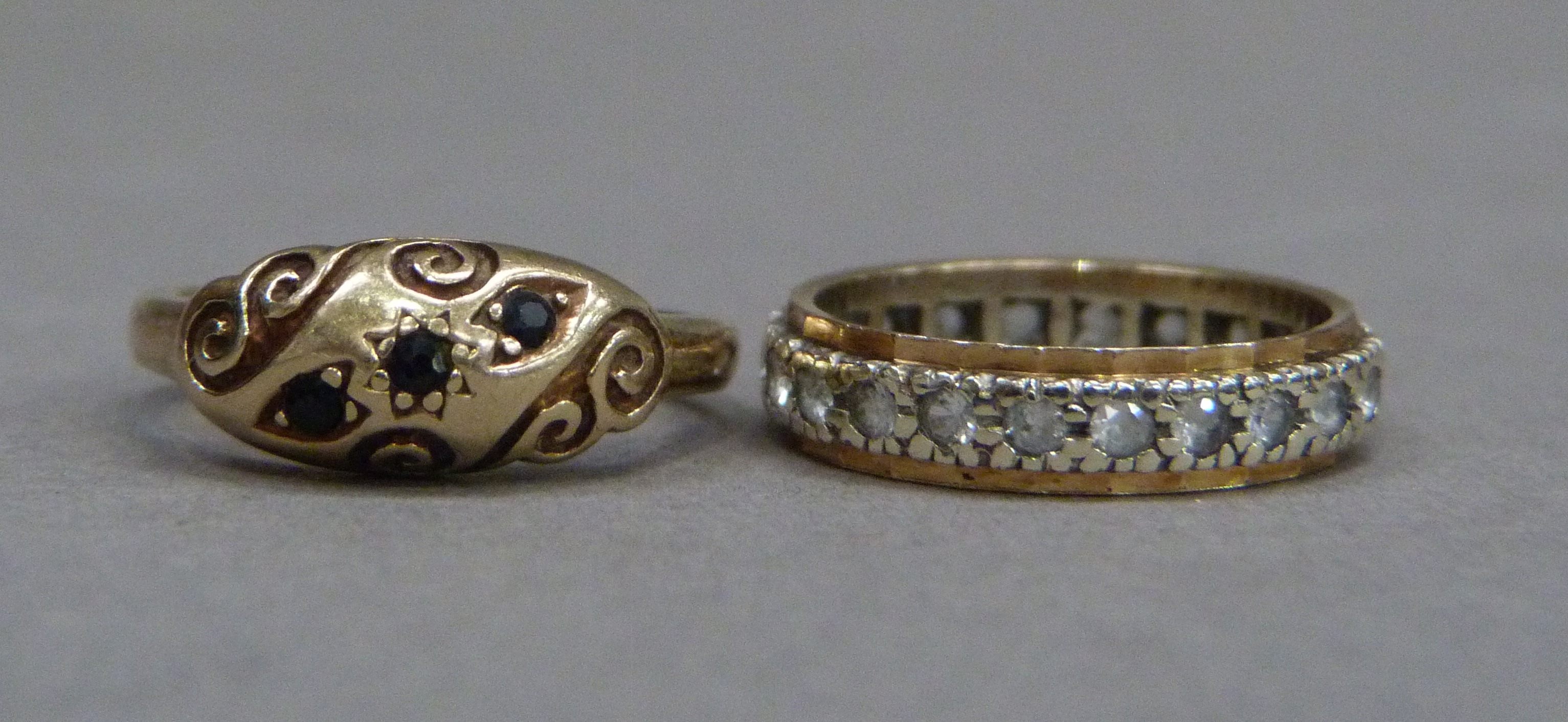 Two 9ct gold rings, a three stone sapphire ring and a colourless spinel eternity ring, total