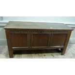 An oak blanket chest, the rectangular hinged lid above a gouge carved triple panel front on tall