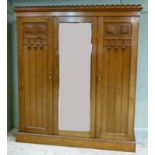 A good Arts and Crafts walnut wardrobe with castellated cornice, the central mirrored door flanked