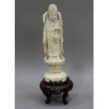 An ivory figure of Guan Yin holding a basket of fish and vase on a stepped base, abalone detail,