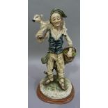 A resin figure of a shepherd carrying lamb over his shoulders and basket of fruit and flowers,