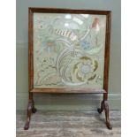 A walnut framed fire screen, the crewel work panel on acanthus carved scrolling legs with conforming