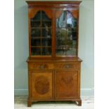 A George III style mahogany bookcase cabinet the flared cornice above a figured frieze and pair of