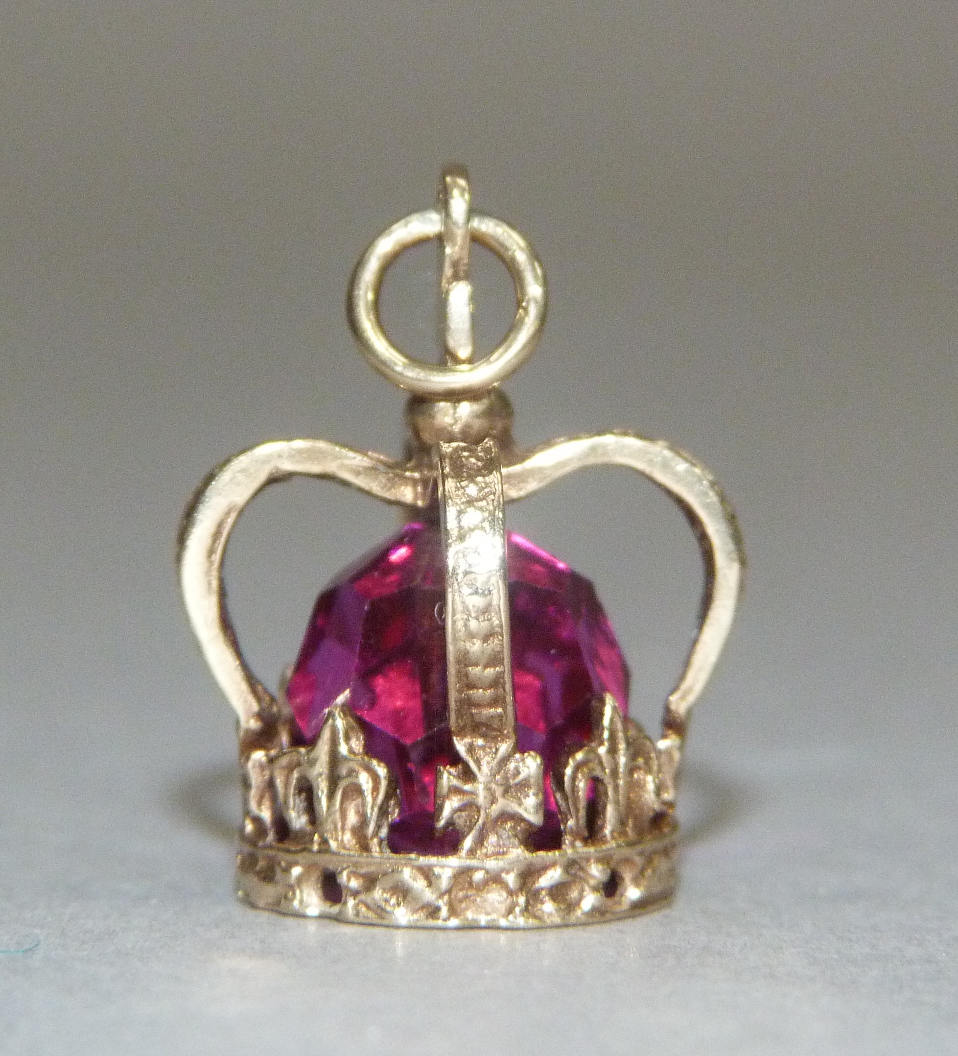 A crown charm in 9ct gold, c.1947, set to the centre with a faceted red paste bead, approximate - Image 2 of 3