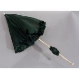 A Victorian ivory and green silk parasol with jointed two section handle carved with an entwined