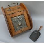 An oak Arts and Crafts coal box having a coppered inset panel of stylised flowers