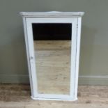 A white painted wooden hanging corner cabinet with flared cornice above a mirrored door, 114cm high