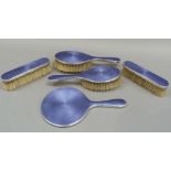 A five piece mauve basse taille enamel and silver dressing table set comprising hand mirror, two