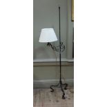 A wrought iron standard lamp with adjustable scrolling branch fitted conical shade, the post