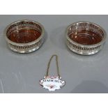 A pair of silver plated bottle coasters in George III style with gardrooned rims and pierced bodies;