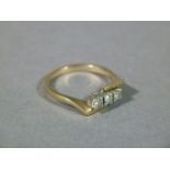 A three stone diamond ring in 9ct gold, the brilliant cut stone claw set in square collet flanked by