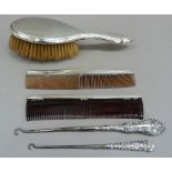 An early 20th century silver backed hair brush; together with two silver backed combs and two silver