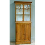 A Victorian stripped pine cupboard the flared cornice above a pair of glazed doors applied with