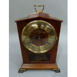 A Warmink mahogany cased mantel clock, the top with loop carrying handle above a chapter ring with