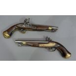A pair of reproduction Tower flintlock pistols with brass capped stocks and hinged ramrods,