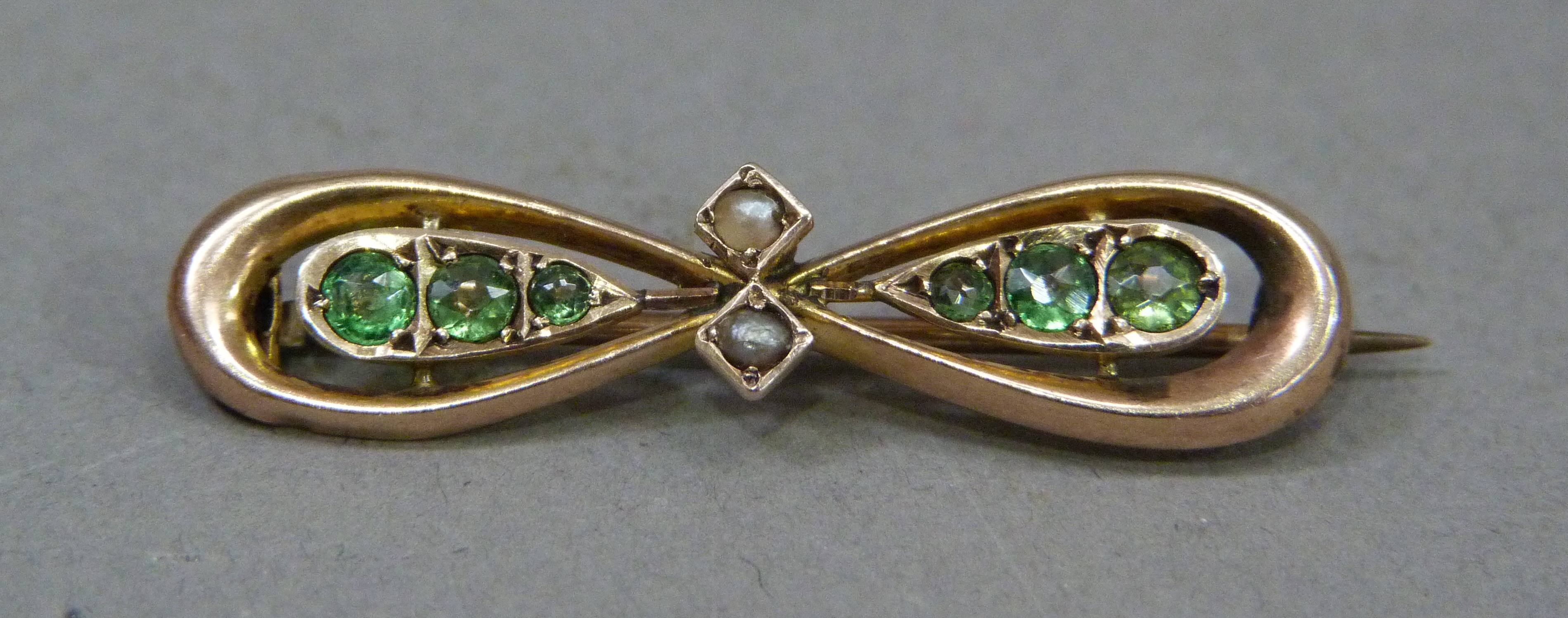 A George V 9ct gold bow brooch set with garnet doublets on seed pearls, approximately 35mm