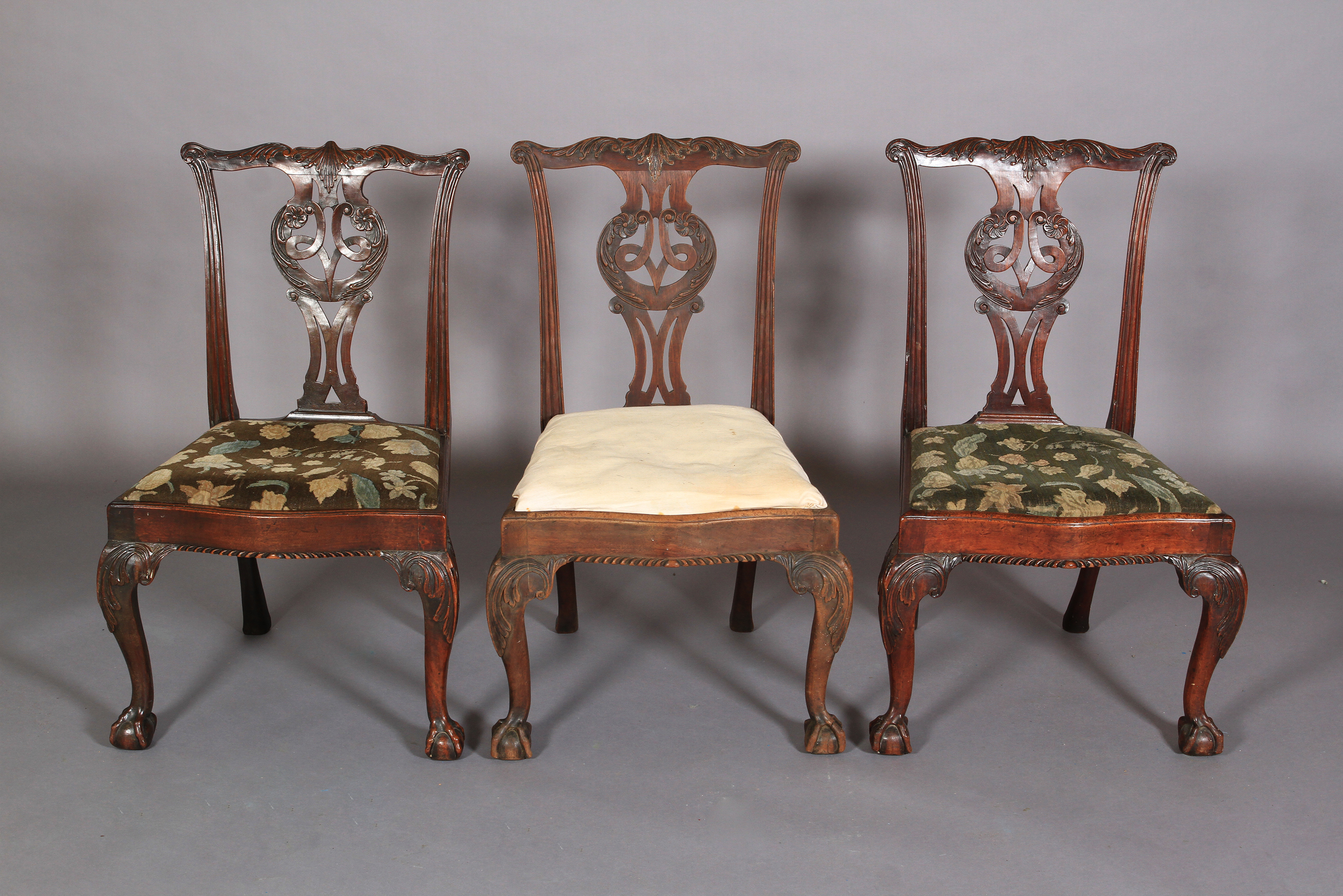 A SET OF THREE 18TH CENTURY MAHOGANY DINING CHAIRS, each having a serpentine top rail carved with