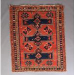 A CAUCASIAN RUG, the fox red field with three large dark blue geometric medallions interspersed with