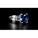 A SAPPHIRE AND DIAMOND RING the oval faceted sapphire claw set raised against tapered baguette cut