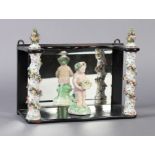 A GERMAN PORCELAIN AND MIRROR LINED EBONISED WALL SHELF, the uprights of floral encrusted and