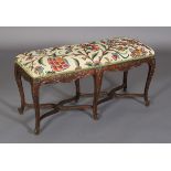 A LATE 19TH CENTURY MAHOGANY LONG STOOL, having a stuffed over crewel work top, serpentine and